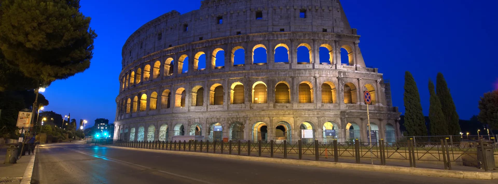 the Roman Colosseum at night backed by a deep blue sky