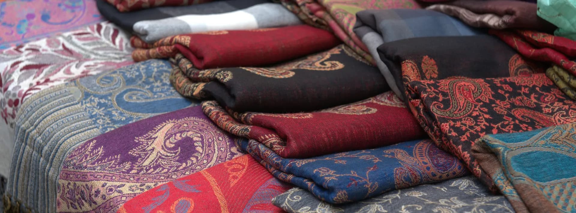 colorful shawls folded on a table at a market in Florence