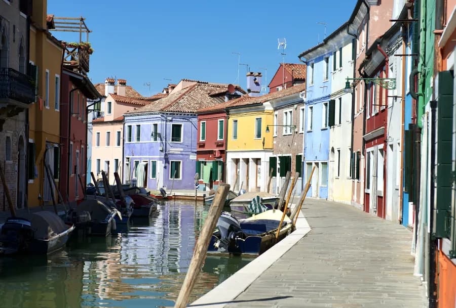 View looking up a canal with anchored boats and colorful buildings in Burano, Italy