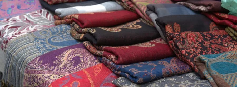 colorful shawls folded on a table at a market in Florence