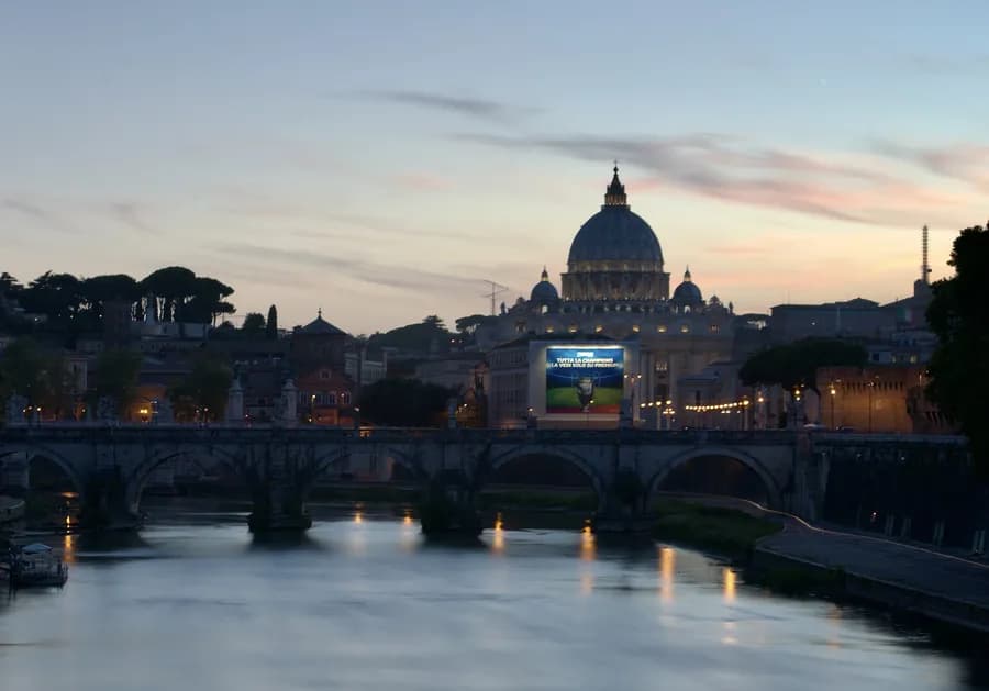 The Ponte Sant'Angelo reflected in the Tiber River with St. Peter's Basilica in the background at night